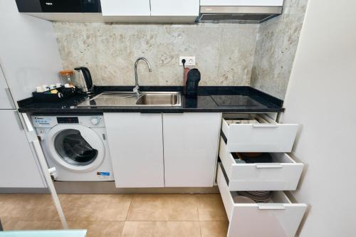 a small kitchen with a sink and a washing machine at Apartamentos Golfinho Dourado in Santa Maria
