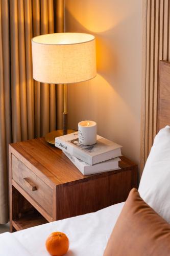 a lamp on a nightstand with a candle and books at DingD0ng Suites - The Sun Avenue - Free Pool & Gym in Ho Chi Minh City