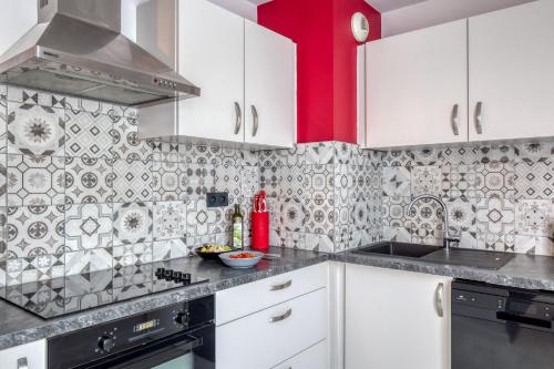 a kitchen with white cabinets and a red wall at Charmant appartement de 46 m2 au cœur de Décines in Décines-Charpieu