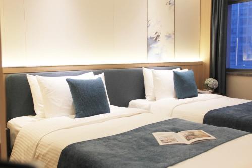 two beds in a hotel room with a book on them at Oakwood Central Wuxi in Wuxi
