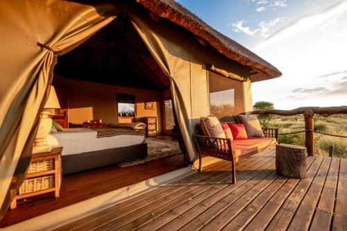 a bed and a chair on a wooden deck at South Okavango - Omogolo Hideaways in Rammu