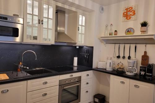 une cuisine avec des armoires blanches et des comptoirs noirs dans l'établissement New apartment next to the Briançon slopes, à Briançon