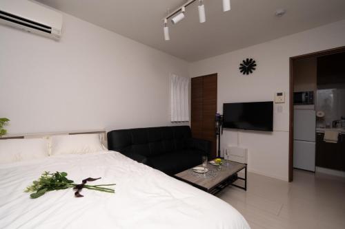a bedroom with a large white bed and a couch at Park side stay Shinjuku in Tokyo
