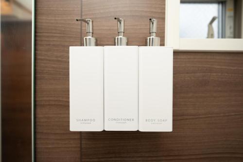 three white towels hanging on a wooden wall at Park side stay Shinjuku in Tokyo