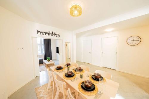 a dining room with a table and chairs and a clock at Urban Luxe 70 m2 Two-Bedroom Apartment GB-62 in Eindhoven
