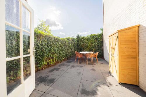 a patio with a table and chairs next to a hedge at Urban Luxe 70 m2 Two-Bedroom Apartment GB-62 in Eindhoven