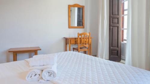 a bedroom with a white bed with towels on it at Hostal Centro in Toledo