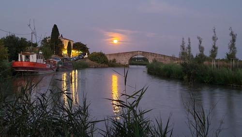 a river with a bridge and a boat in the water at Le N 9 in Argeliers