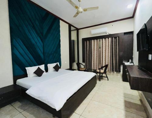 Un dormitorio con una cama, un escritorio y un televisor. en Hotel Mayur, en Alwar