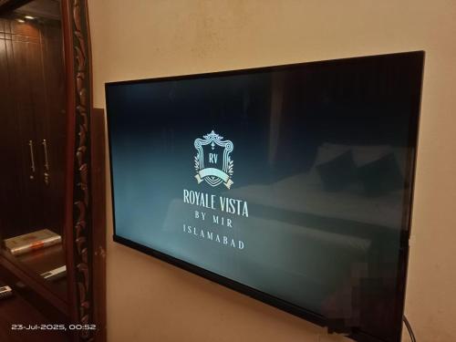 a television screen with a sign on a wall at ROYALE VISTA by MIR in Islamabad
