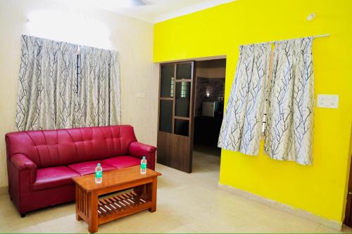 a living room with a red couch and a table at Siesta Inn - RP Resort in Chennai