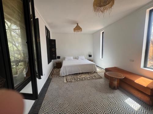 a white bedroom with a bed and a rug at Ecolodge Dar bouhouta in Tahannout