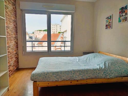 une chambre avec un lit et une grande fenêtre dans l'établissement Appartement confortable à proximité du centre ville, à Reims