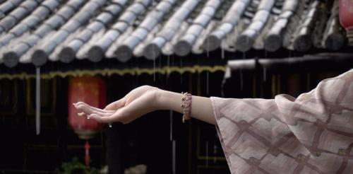 a woman with her hand out in front of a building at Yiyuan Snow Mountain View Historical Naxi House - Lijiang Old Town Mufu branch in Lijiang