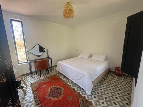 a bedroom with a bed and a table and a window at Ecolodge Dar bouhouta in Tahannout