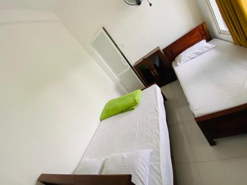 a small room with two beds and a green pillow at TK Homes in Badulla