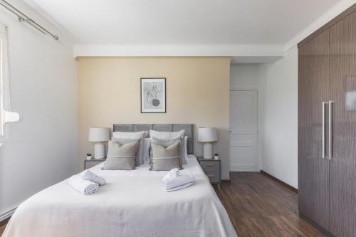a white bedroom with a large bed with white sheets and pillows at Majestueux Appartement 2 pièces à Hydra in Hydra