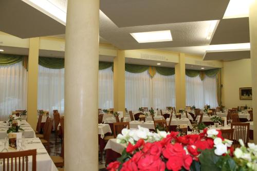 a banquet hall with tables and red flowers at Terme Villa Pace in Abano Terme