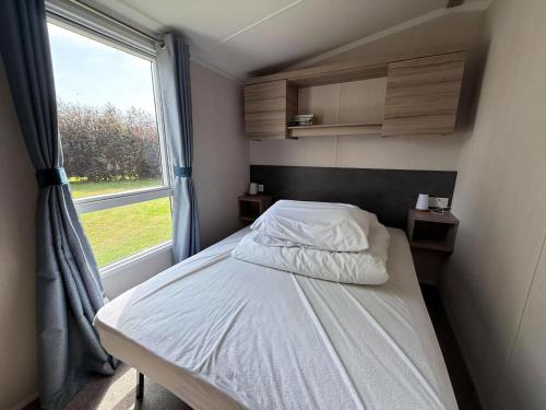 a bed in a small room with a window at Charming 8 Berth Caravan At Cherry Tree Holiday Park In Norfolk Ref 70831C in Great Yarmouth