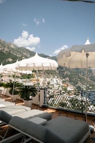 a balcony with white umbrellas and a view of a city at Hotel Conca d'Oro in Positano