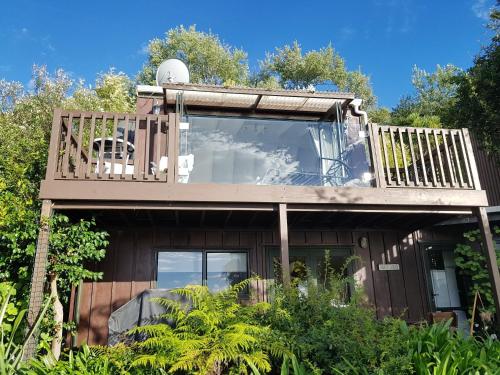 a house with a deck with a balcony at Rangimarie Anaura Bay Beachstay in Anaura Bay