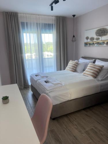 a white bedroom with a large bed and a window at Vrnjačko Vrelo Resort in Novo Selo