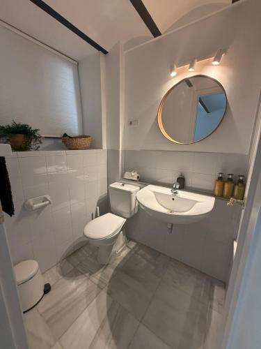 a bathroom with a toilet and a sink and a mirror at TYP Sevilla in Seville
