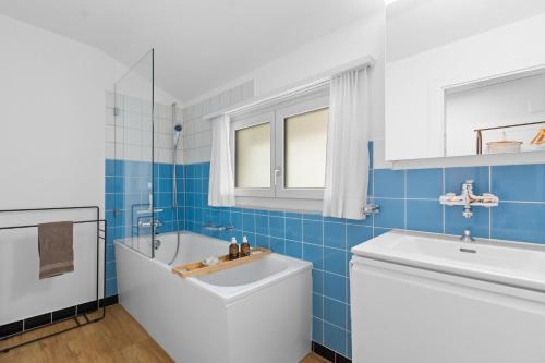 a blue tiled bathroom with a tub and a sink at Ferienwohnung 'Bergkristall' in Schiers