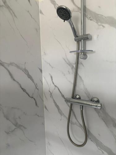 a shower with a shower head on a marble wall at Refurbished 4-Bed Home Near Hospital & Station in Chatham