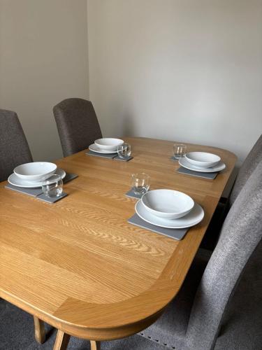 a wooden table with plates and glasses on it at Refurbished 4-Bed Home Near Hospital & Station in Chatham