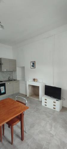 a white kitchen with a table and a desk at Casa vacanza Larimar tipico stazzo gallurese in Terme di Castel Doria