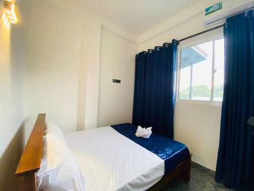 a white cat sitting on a bed in a bedroom at TK Homes in Badulla