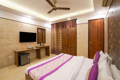 a bedroom with a large bed and a tv at Hotel South Delhi Inn Just 10 Minute Away Form Nizamuddin Railway Station in New Delhi