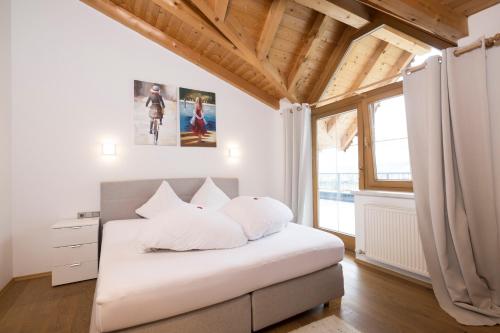 a bedroom with a bed with white pillows and a window at Appartements Huber in Fügen