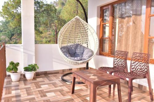 a porch with a hanging swing and two chairs and a table at City Central Inn Hotel !! in Kasauli