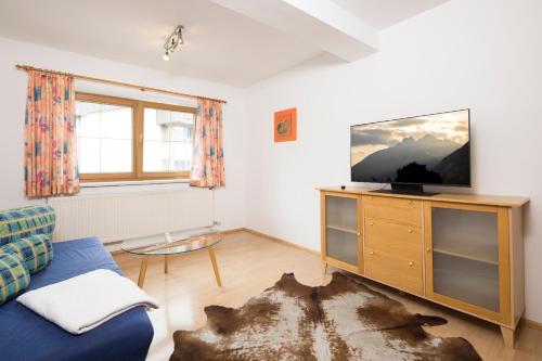 a living room with a tv and a blue couch at Appartements Huber in Fügen
