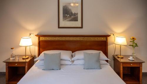 a bedroom with a white bed with two lamps on tables at Hotel Donatello in Padova