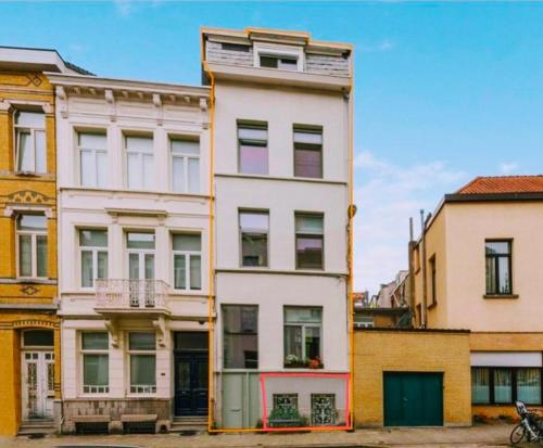 a tall white building in front of some buildings at J1 - Urban studio in Antwerp in Antwerp