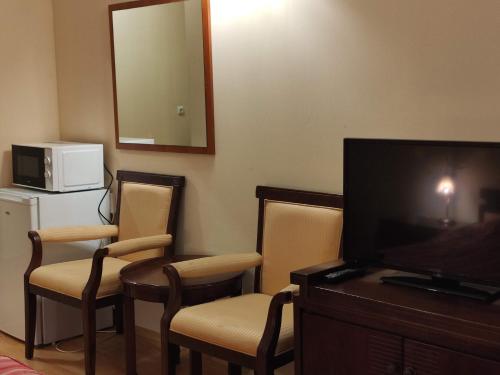 a hotel room with a tv and chairs and a mirror at Beachfront apartment in 4star Hotel - Kiten in Kiten
