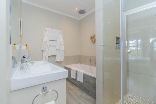 a white bathroom with a sink and a shower at Whale Rock Luxury Lodge in Hermanus