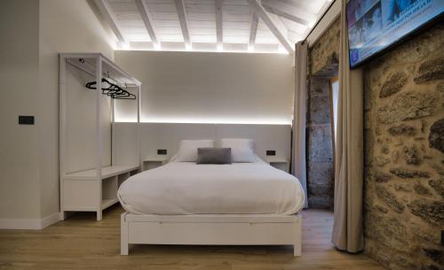Un dormitorio con una cama blanca en una habitación. en Loft Faro 2, en Finisterre