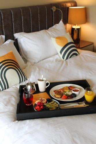 a tray with a tray of food on a bed at voco The Club - Dublin Gateway by IHG in Naas