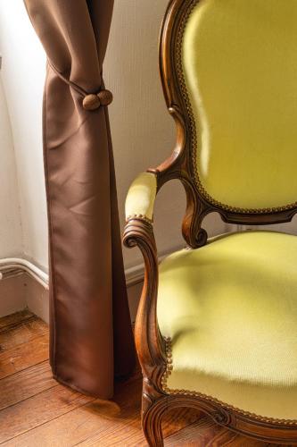 a yellow chair next to a room with a curtain at Domaine La Belle Histoire - Gîte côté jardin in Besset