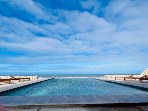 a swimming pool with the ocean in the background at Taghza house caravane in Essaouira