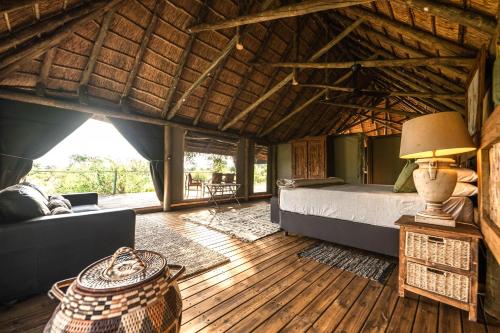 a bedroom with a bed and a couch in a room at South Okavango - Omogolo Hideaways in Rammu