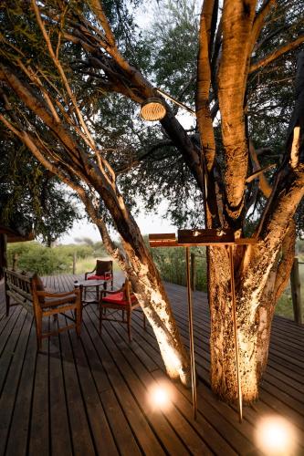 a tree with a table and chairs on a deck at South Okavango - Omogolo Hideaways in Rammu