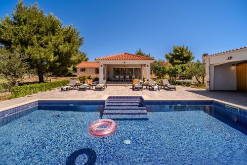 a swimming pool with a frisbee in the water at Luxury Villa Nature with heated private pool, sauna & fire pit, a short walk to the beach in Milna