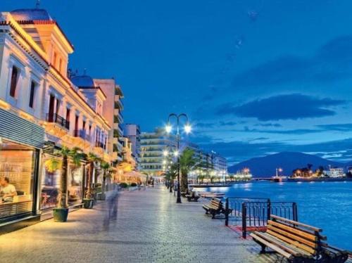 a street with benches next to the water at night at Angela's Apartment in Chalkida