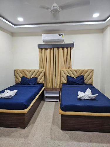 2 letti in una camera con lenzuola blu e scarpe bianche di Mehmaan Guest House a Hyderabad
