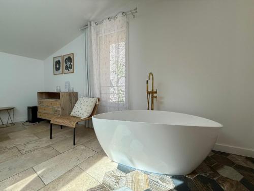 a large white bath tub in a room with a chair at Hotel Restaurant O'Banel in Gallargues-Le-Montueux